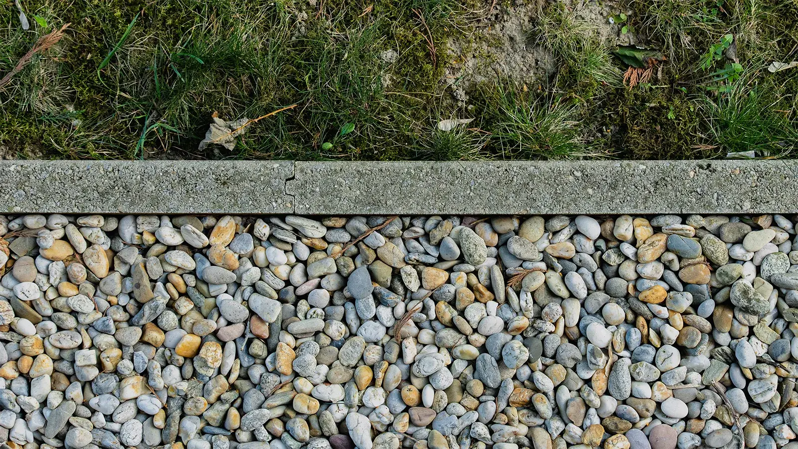 gravel materials with a cement border and grass on the opposite side