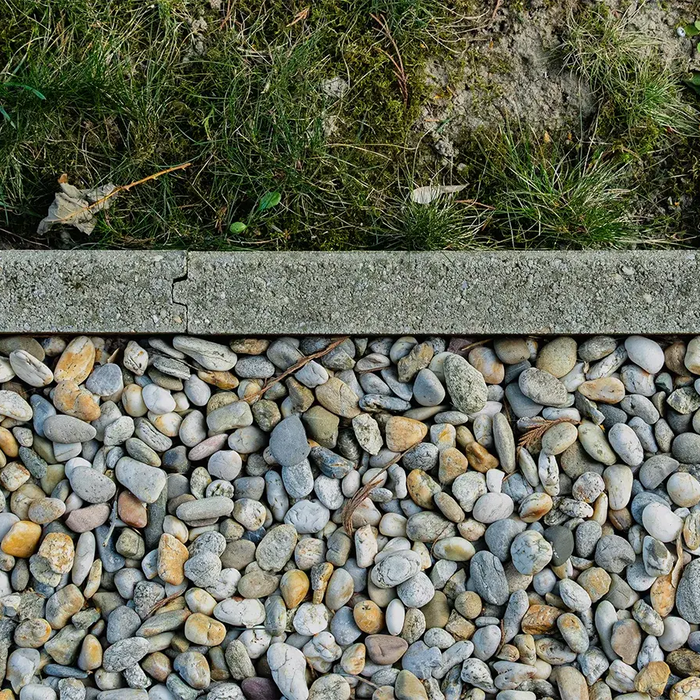 gravel materials with a cement border and grass on the opposite side