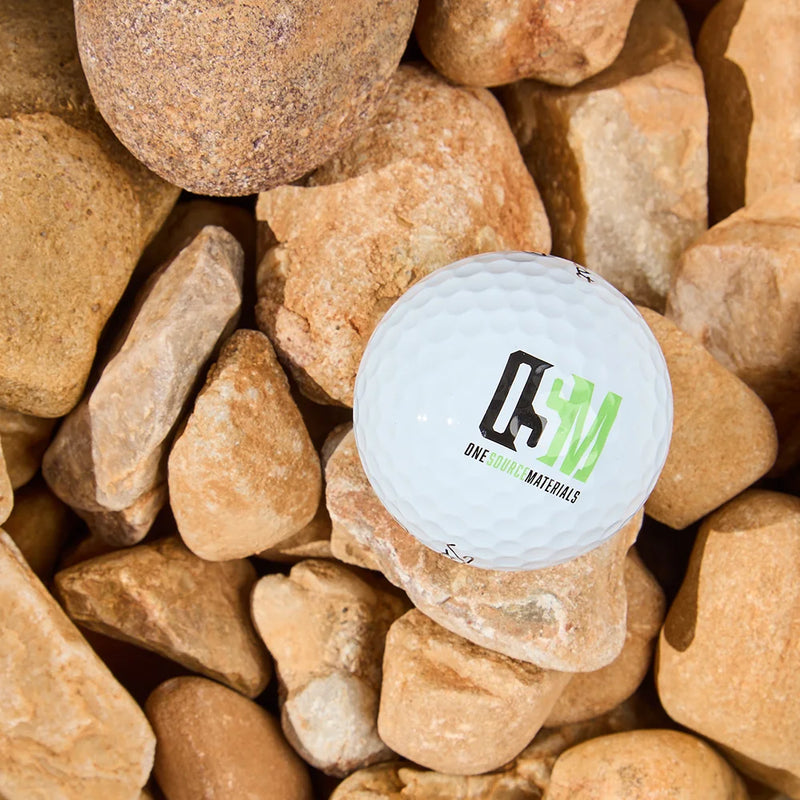 White golf ball with a logo on a bed of brown stones