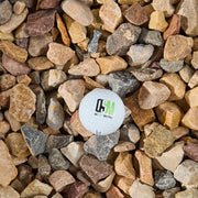 Close-up of multicolored stones with a branded white golf ball in the center.