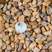 White ball with the One Source Materials logo on a bed of multicolored stones
