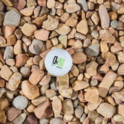 Golf ball with a logo on a bed of multicolored stones