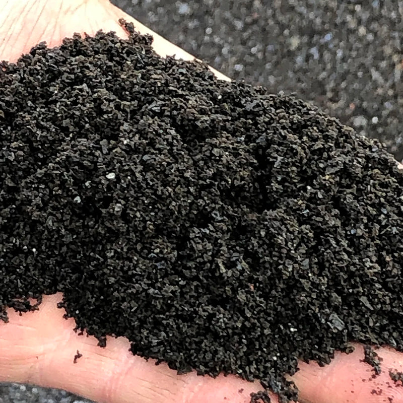 Hand holding a scoop of dark lava fines