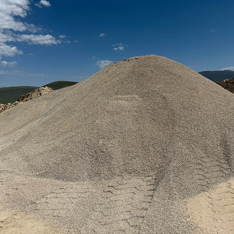 Large mound of crusher fines under a clear blue sky