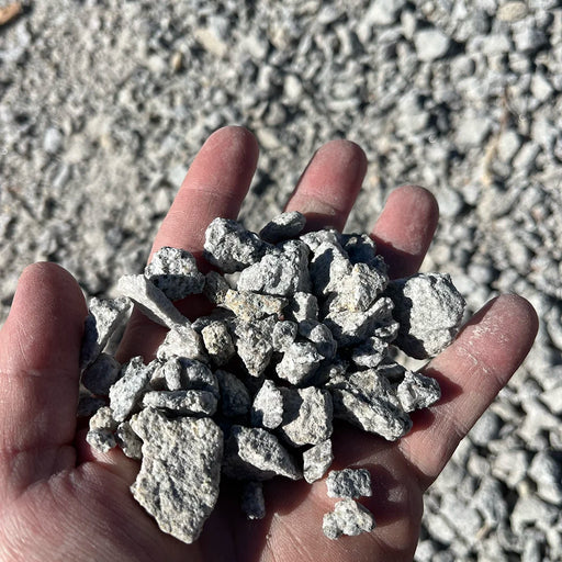 Hand holding small rocks against a gravel background