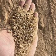 Hand holding a small amount of fines against a sandy background