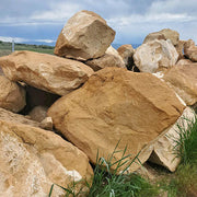 Large brown stones with grass at the base under a blue sky