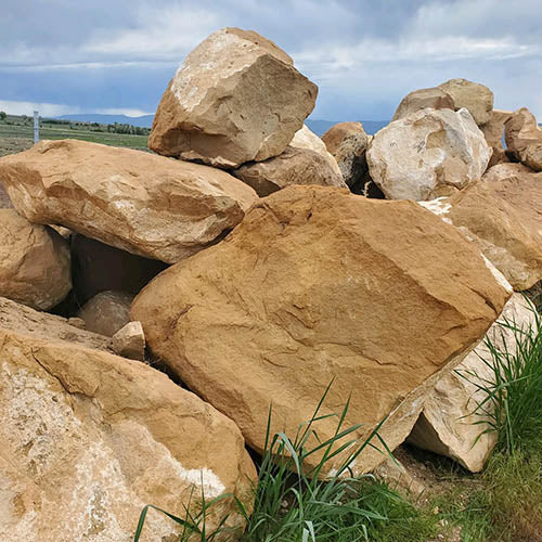 Large brown stones with grass at the base under a blue sky