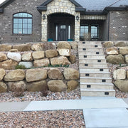 Staircase leading up to a house with stone wall and decorative elements.