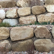 Stone wall with large beige stones and smaller pebbles in the foreground