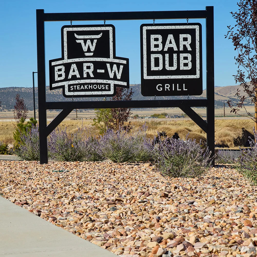 Outdoor sign for Bar-W Steakhouse and Bar-Dub Grill with a desert landscape in the background.