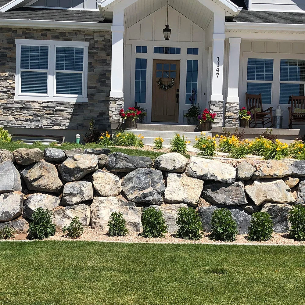 Front of a house with a stone wall, flowers, and a wreath.