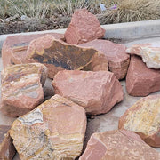 Collection of large, multicolored boulders on a concrete surface with grass in the background