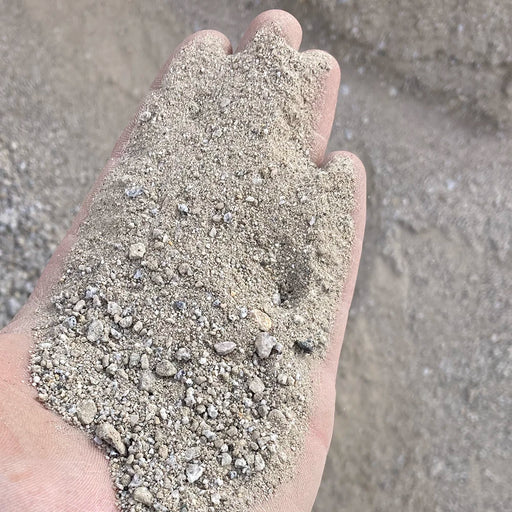 Hand holding a small amount of sand with a sandy background