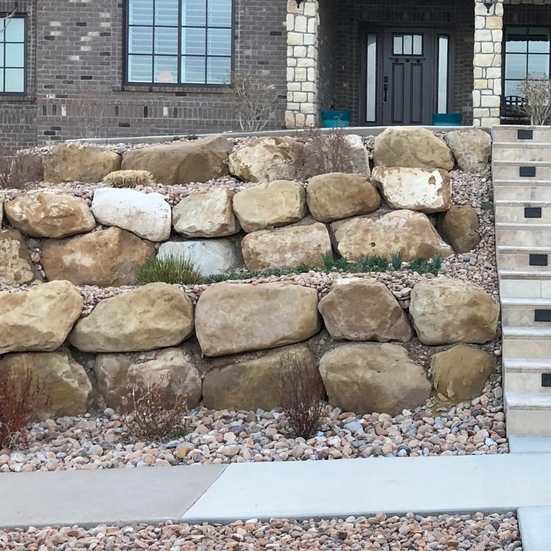 Rock wall in front of a house with a gray door