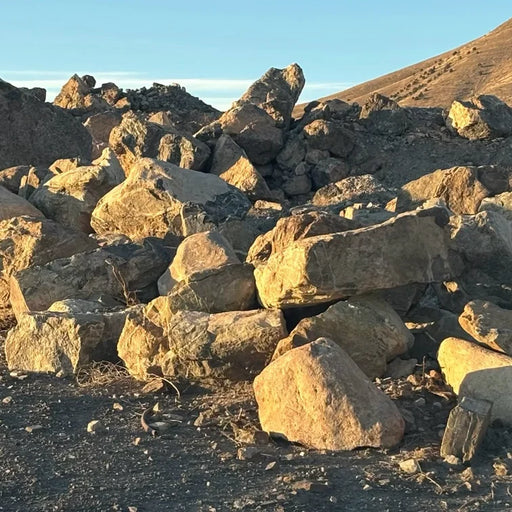 Pile of boulders on a hillside with a clear sky.