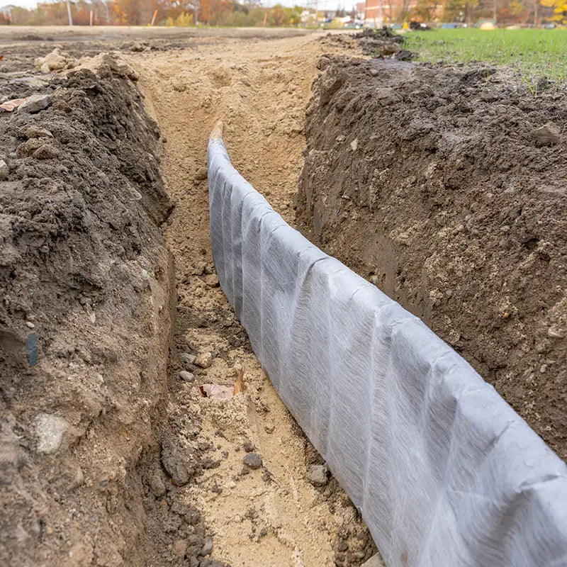 Construction photo of natural turf athletic field vertical edge drain profile, drainage panel between baseball / softball infield clay and natural grass field.