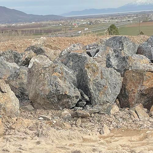 Large rocks and boulders on a construction site with a distant landscape.